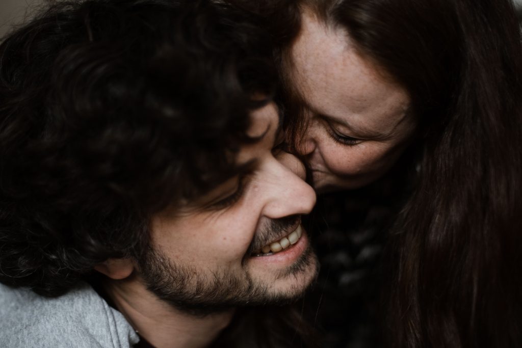 eine Frau küsst ihren Mann auf die Wange, beide haben geschlosene Augen
