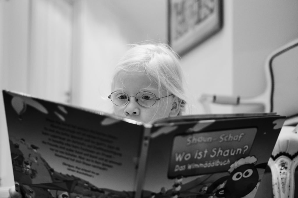 ein Mädchen hält ein großes Buch in der Hand und schaut in das aufgeschlagen Buch 