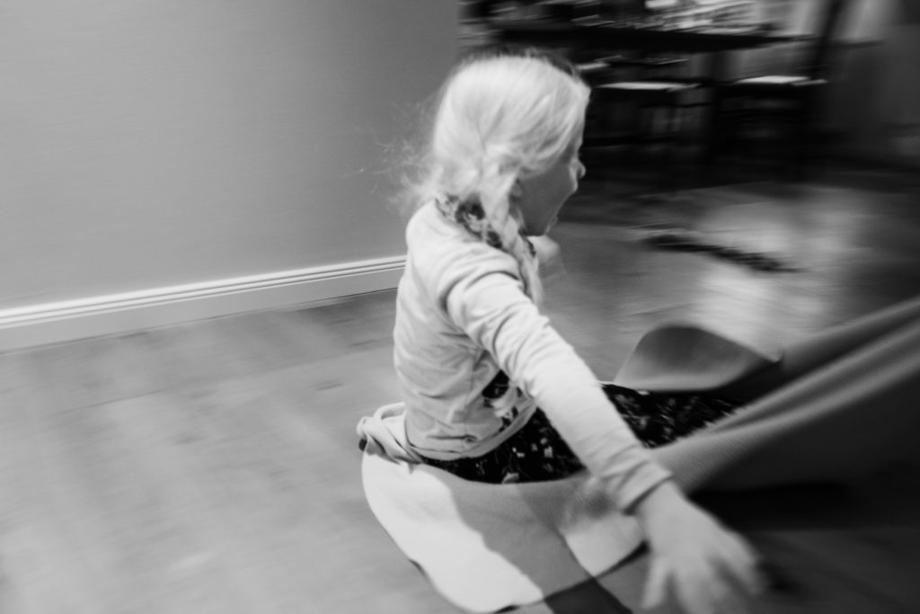ein Mädchen sitzt auf dem Boden in ihrem Kinderzimmer, sie sitzt auf einem Laken und hält die Arme ausgestreckt