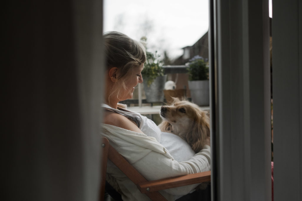 eine schwangere Frau sitzt mit ihrem Hund auf dem Balkon, der Hund und die Frau schauen sich an