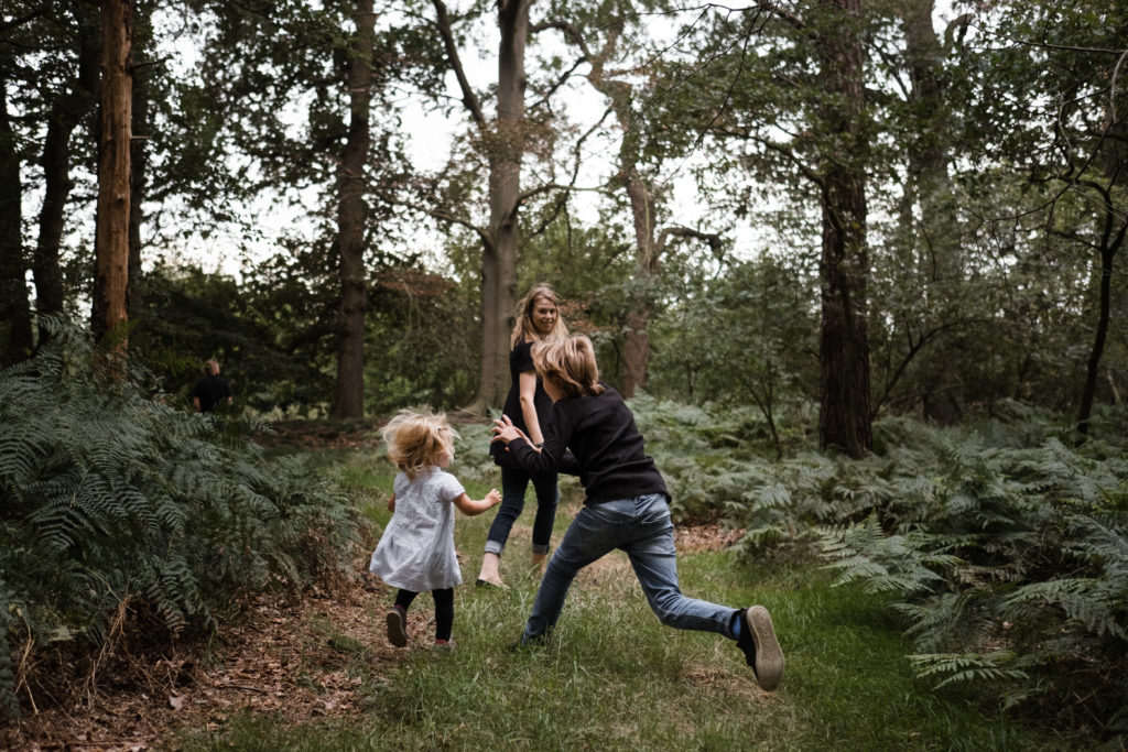 in einem Wald ist eine Mutter mit ihrem Sohn und ihrer kleinen Tochter, die Mutter geht vor ihren Kindern, mit Blick auf sie gerichtet, die beiden Kinder laufen hinter ihr her