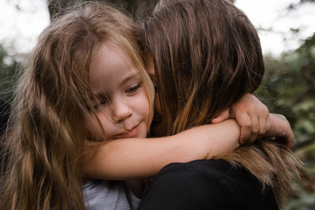 eine Mutter und ihre Tochter, die Tochter legt ihre Hände um den Hals der Mutter