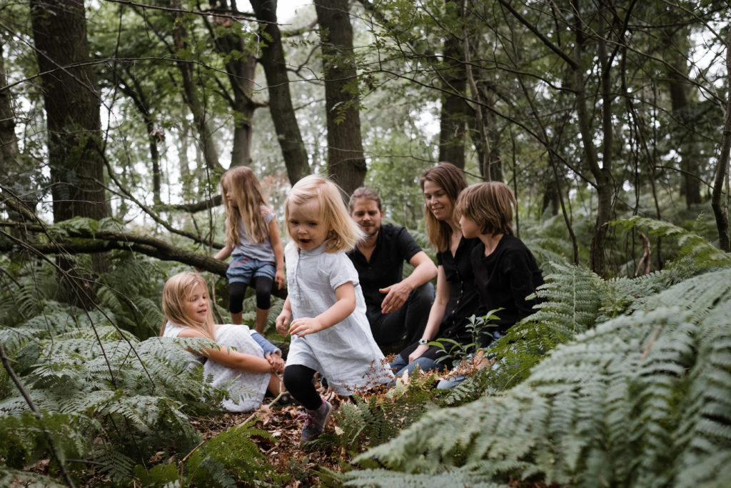 im Wald sitzen eine Mutter und ein Vater inmitten Fahn mit ihren 3 Töchtern und ihrem Sohn