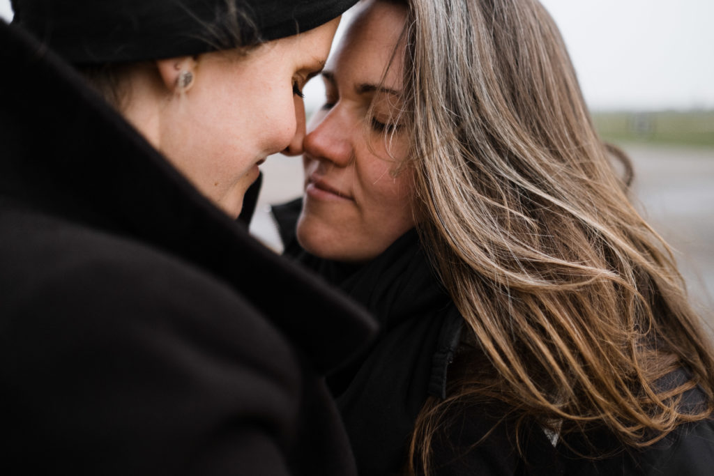 2 Frauen stehen auf dem Rollfeld des alten Flughafen in Berlin, sie sind beide schwarz gekleidet, ihre Nasen berühren sich, beide schließen die Augen
