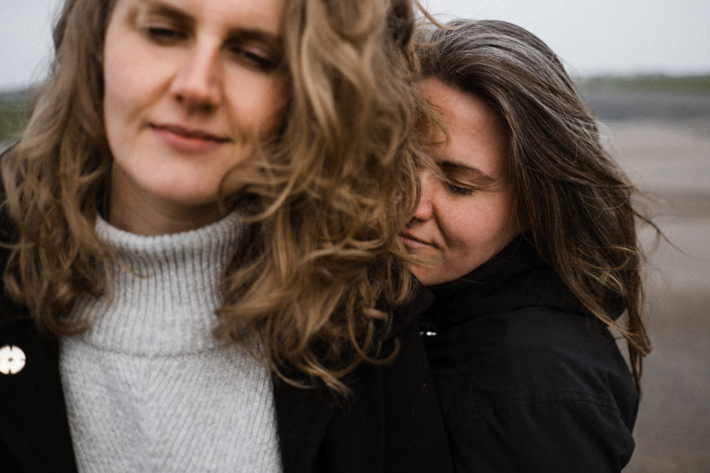 auf dem alten Rollfeld des Flughafen in Berlin stehen 2 Frauen, beide schließen die Augen, eine Frau lehnt sich an den Rücken der anderen Frau